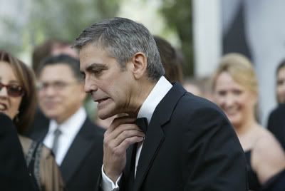 headshot of George Clooney looking very uncomfortable and jutting out his chin as he tries to loosen his tie