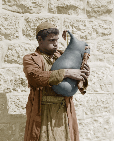 1898-1946 Young Bedouin man blowing (bagpipe) instrument. 1898-1946 Young Bedouin man blowing (bagpipe) instrument.