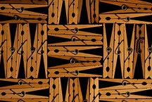 a neat abstract pattern of hinged wooden clothespins against a black background