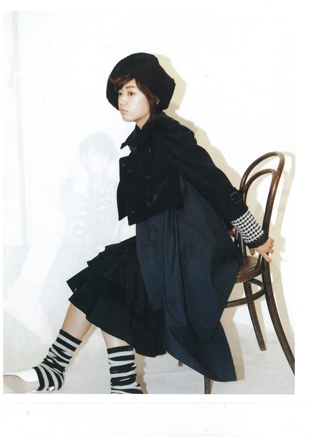 Navy trench coat, long black skirt, ruffles, Hound Tooth Check 
Shirt by Bundeosyop Kkomdegareusong, all white patent oxford shoes and a
 collection of knit hats and warmers by stylists.