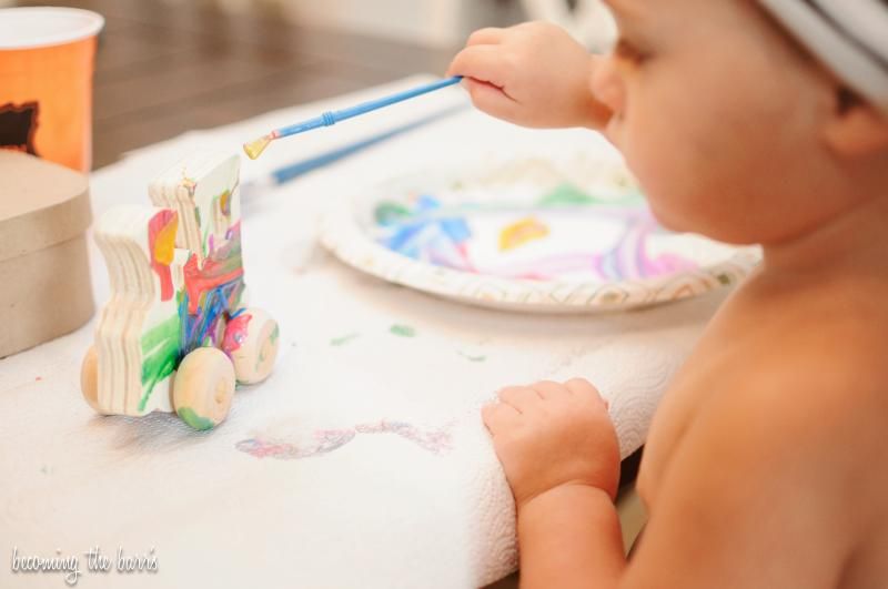 toddler painting a wooden toy