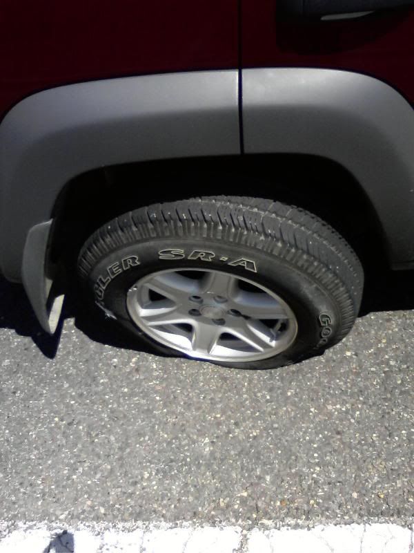 My tire is wedged between my Jeep and the road.