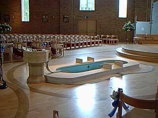 This font at St. Joseph's Catholic Church in Surrey, England is in the center of the church. You can see part of the circles on the floor which emphasise three phases in our relationship with God: listening to his Word (lectern or ambo), being received into his family (baptism), partaking of his Eucharistic feast at the altar.