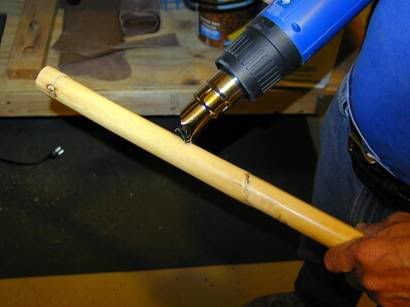 Heating the rattan with skin on to prepare it for straightening.