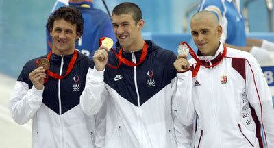 Michael Phelps holds his gold medal on the podium on August 10, 2008. Pictured with Ryan Lochte and László Cseh.