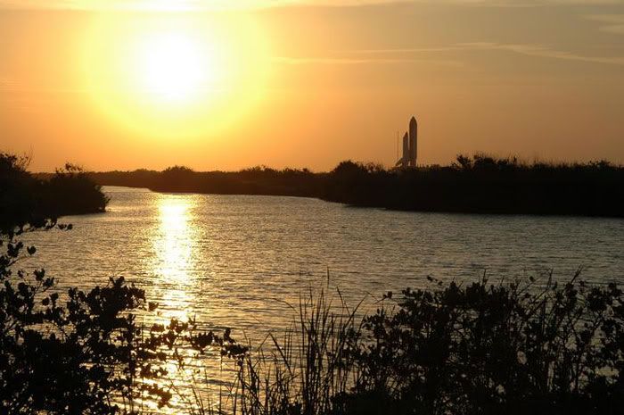Space Shuttle Discovery rolls out to its launch pad as the Sun sets.