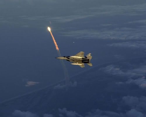 An F-15 fighter jet patrols the skies above Kennedy Space Center just as a space shuttle is lifting off.