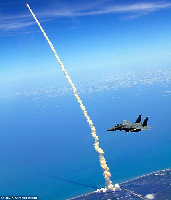 An F-15E Strike Eagle patrols the skies above Kennedy Space Center...as space shuttle Atlantis launches on flight STS-132 on May 14, 2010.