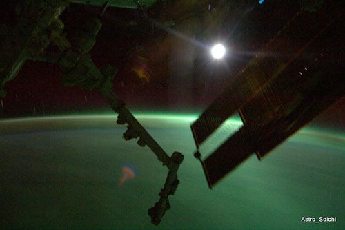 The ISS flies over an aurora while orbiting the dark side of the Earth, on April 6, 2010.  The Moon looms in the background.