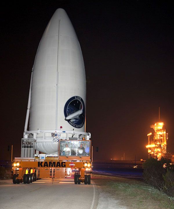 With space shuttle Discovery in the background, the Atlas V payload fairing carrying the OTV is transported to its launch pad, ahead of its March 2011 liftoff from Cape Canaveral Air Force Station in Florida.