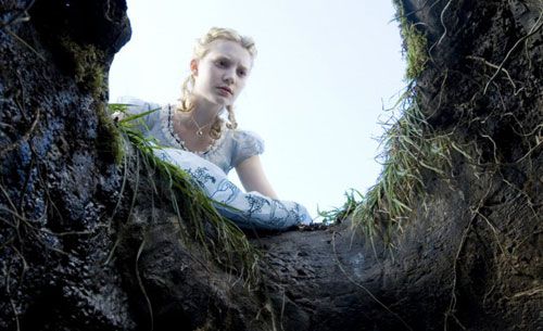 Alice (Mia Wasikowska) peeks into the rabbit hole in ALICE IN WONDERLAND.
