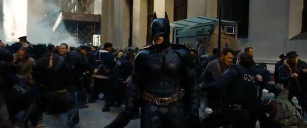 Batman (Christian Bale) watches as Gotham police officers and Bane's mercenaries clash with each other in THE DARK KNIGHT RISES.