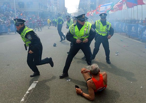 Police officers stand guard near a fallen runner after an explosion takes place at the Boston Marathon on April 15, 2013.