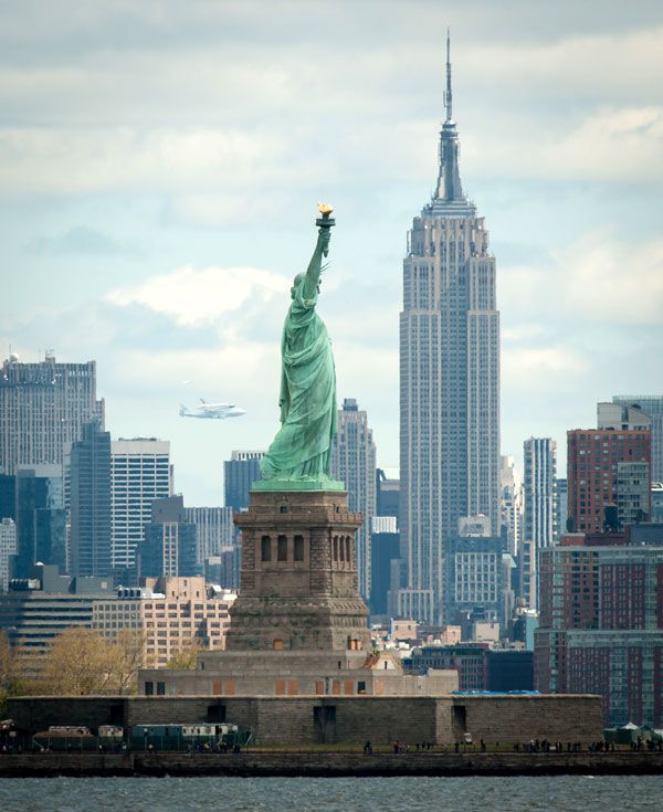 With the Statue of Liberty and Empire State Building in the foreground, the shuttle Enterprise and NASA 905 fly over New York City on April 27, 2012.