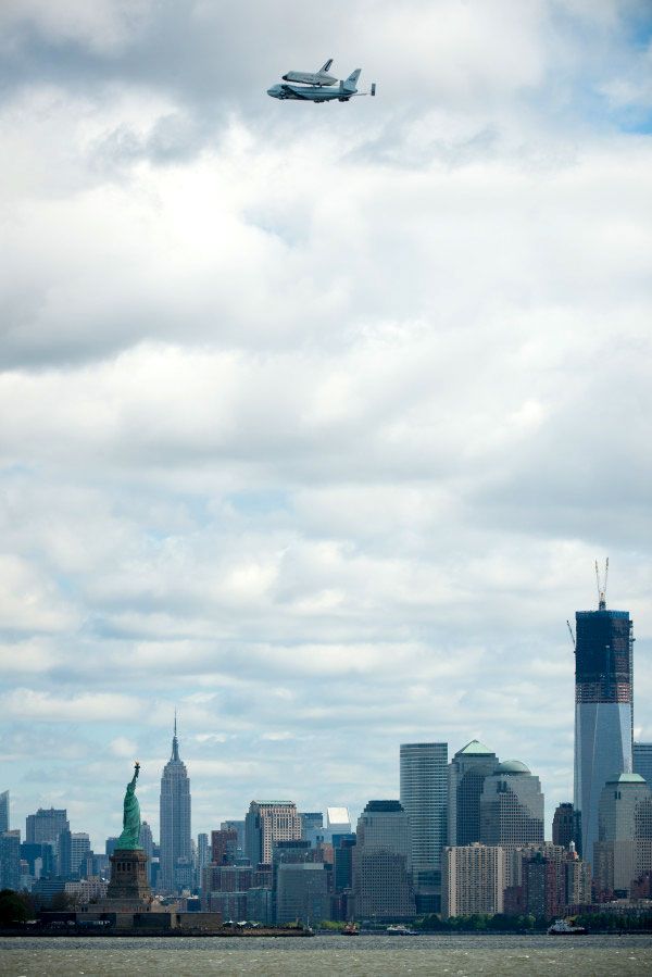 With the Statue of Liberty, Empire State Building and 1 World Trade Center down below, the shuttle Enterprise and NASA 905 fly over New York City on April 27, 2012.