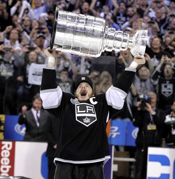 Los Angeles Kings captain Dustin Brown hoists up the Stanley Cup trophy after L.A. wins its very first championship on June 11, 2012.