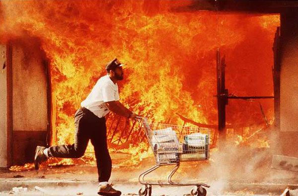 A man runs off with a shopping cart full of looted items during the 1992 Los Angeles riots.