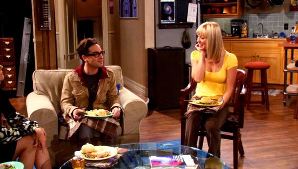 Leonard and Penny turn to look at each other after Mary Cooper (visible near the left of frame) tells them that they make a cute couple in THE BIG BANG THEORY.