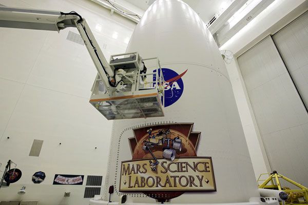 A worker applies a NASA 'Meatball' logo to the side of the Atlas V's payload fairing, on October 31, 2011.
