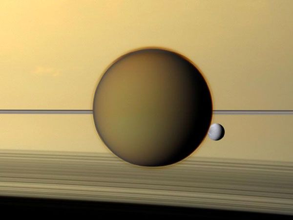 Saturn's third-largest moon Dione can be seen through the haze of its largest moon, Titan, in this natural-color view of the two posing before the planet and its rings from the Cassini spacecraft, on May 21, 2011. 