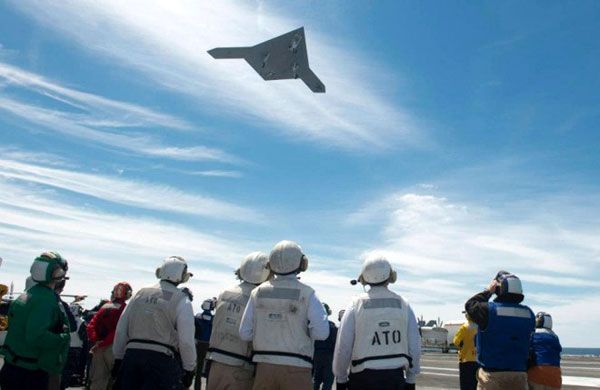 Crew members watch as the X-47B UCAV soars over the flight deck of the USS George H.W. Bush, on May 14, 2013.