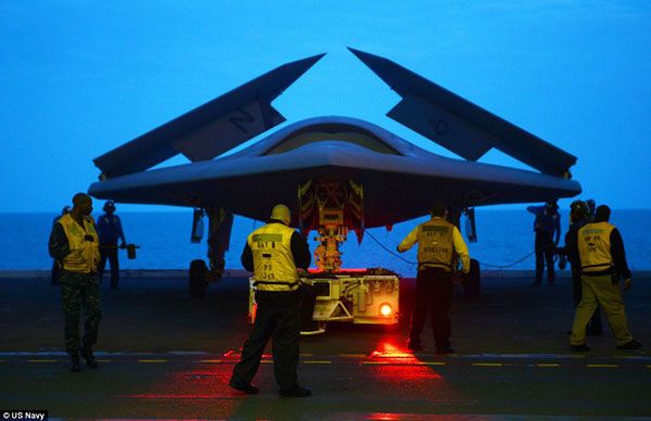 The Sun is about to rise as crew members prepare the X-47B UCAV for its first catapult launch from the flight deck of the USS George H.W. Bush, on May 14, 2013.