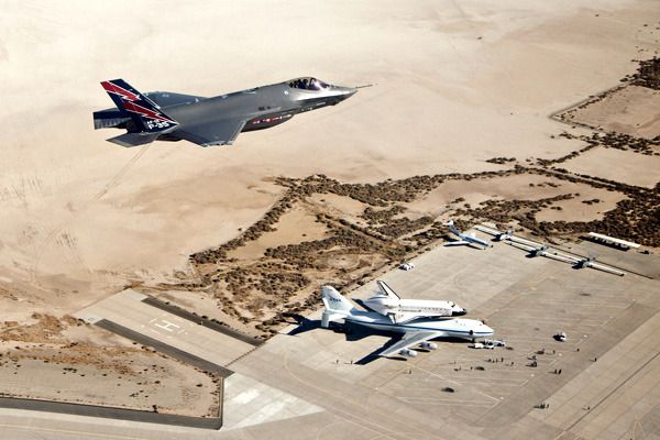 An F-35A Lightning II flies above space shuttle Endeavour and her Shuttle Carrier Aircraft just as they were about to depart from Edwards Air Force Base in the Mojave Desert and head for Los Angeles...on September 21, 2012.