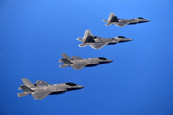 A pair of F-22 Raptors and two F-35 Lightning IIs fly in formation for a training mission.