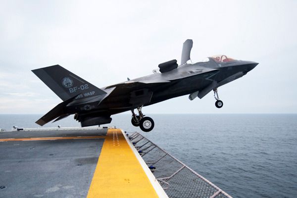 An F-35B Lightning II fighter jet takes off from an L-Class aircraft carrier at sea.