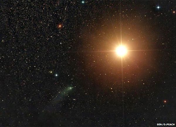 An image of comet Siding Spring (green smear at lower-left of center frame) passing by the bright orange globe of Mars...as seen by astrophotographer Damian Peach on October 19, 2014.
