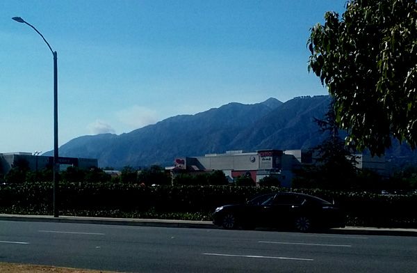 A cloud of smoke is visible (towards the left of this image) behind the San Gabriel Mountains near Santa Anita Mall...on July 24, 2016.