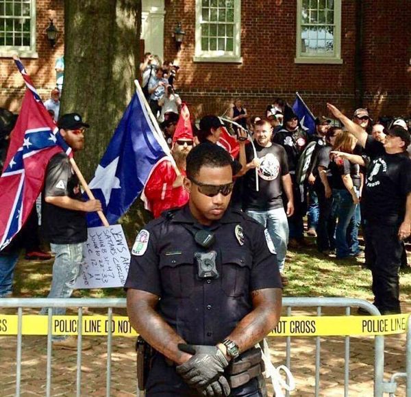 As Neo-Nazi scumbags march behind him, an African-American police officer does his duty providing protection for this filth that it doesn't deserve.