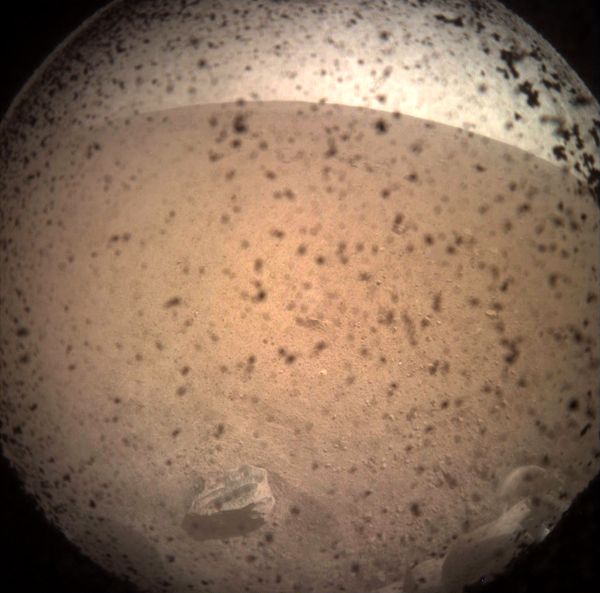 A dusty image of the Martian surface that was taken by a camera (with its lens cover still on) mounted below the deck of the InSight lander...on November 26, 2018.