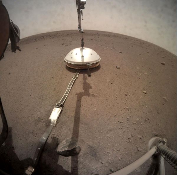 The Wind and Thermal Shield dome is placed atop the seismometer by the InSight lander's robotic arm...on February 2, 2019.