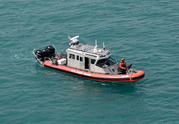 An armed U.S. Coast Guard patrol boat escorts the Norwegian Jade as she heads out to the open sea on March 12, 2018.