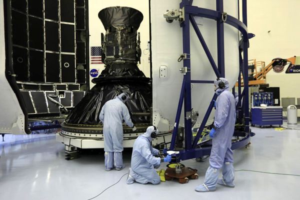 Engineers prepare to encapsulate NASA's TESS satellite with the payload fairing for SpaceX's Falcon 9 rocket at Kennedy Space Center in Florida...on April 9, 2018.