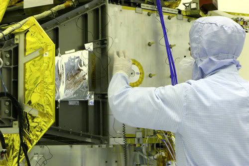 An engineer installs a compact disc bearing the names of 434,738 people onto the side of the New Horizons spacecraft...prior to launch in January of 2006.
