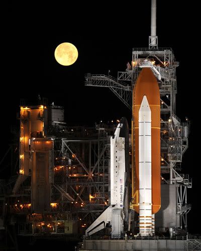 A full moon shines above space shuttle DISCOVERY at Launch Complex 39A, during the early morning hours of March 11, 2009.