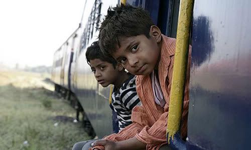 Young Jamal (Ayush Mahesh Khedekar) and his brother Salim (Azharuddin Mohammed Ismail) hitch a ride in SLUMDOG MILLIONAIRE.