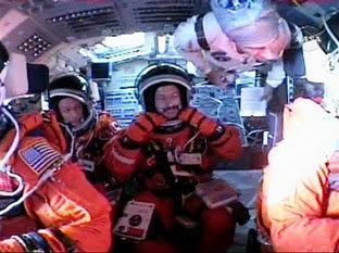 Astronaut Daniel Burbank, center, adjusts his launch and entry suit while sitting in space shuttle Atlantis at the Kennedy Space Center in Florida on September 9, 2006.  Pilot Chris Ferguson, front left, Canadian astronaut Steve MacLean , left, an unidentified NASA worker, top right, and Commander Brent Jett, right , are visible on Atlantis' flightdeck.