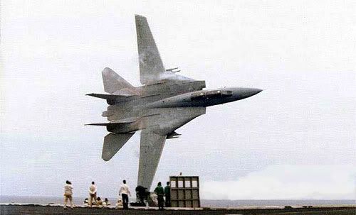An F-14 Tomcat does an extremely close flyby of the nuclear-powered aircraft carrier, USS Stennis.
