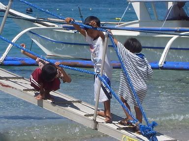 Local children clamber up a banca anchored to the shores of White Beach