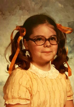 my third grade school picture, in which I'm wearing a lacy peach top and oversized glasses, with my hair in pigtails tied with orange ribbons