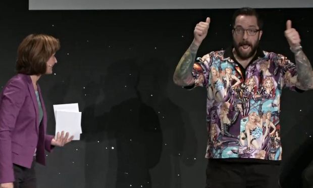 image of Taylor, a thin white tattooed man giving the thumbs-up during the broadcast while wearing the inappropriate shirt
