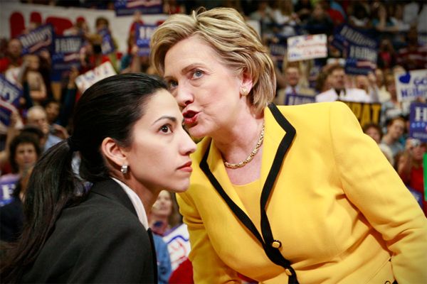 image of Hillary Clinton leaning over to whisper something in the ear of Huma Abedin, a thin Indian-Pakistani-American woman