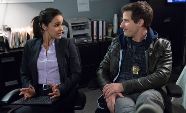 image of actress Melissa Fumero, a young Latina woman, and actor Andy Samberg, a young Jewish man, on the set of Brooklyn Nine-Nine as Detectives Amy Santiago and Jake Peralta