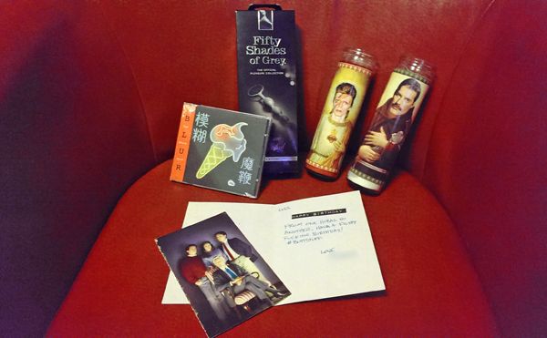 image of the opened card, with random book page tucked inside, Blur's latest CD, a '50 Shades of Grey' Officially Licensed Anal Beads, and two religious candles with the heads of the saints replaced with Freddie Mercury's and David Bowie's heads