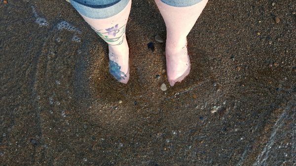 image of my feet in the water, half buried in sand