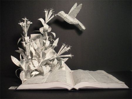 image of a book sculpture in which flowers and a hovering hummingbird are constructed from the pages of a book