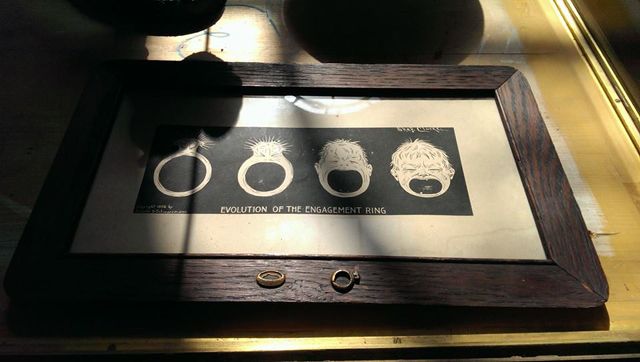 image of a wall hanging that reads: 'Evolution of the engagement ring' and features four images of an engagement ring slowly morphing into the head of a crying baby